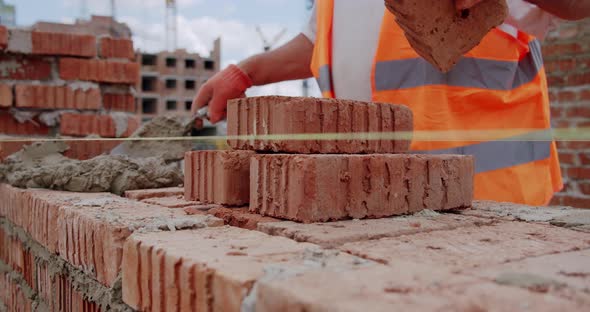 Male Worker Lays Brick Into Wall with Cement Using Trowel. Close Up V2