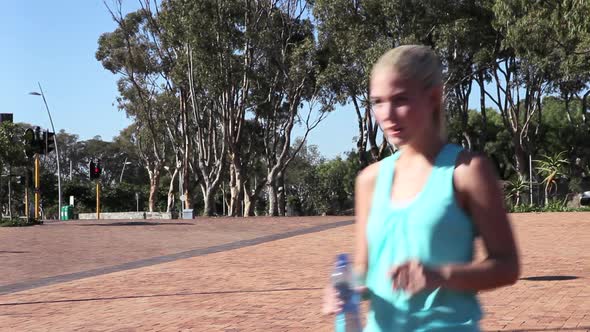 Young woman jogging and drinking mineral water