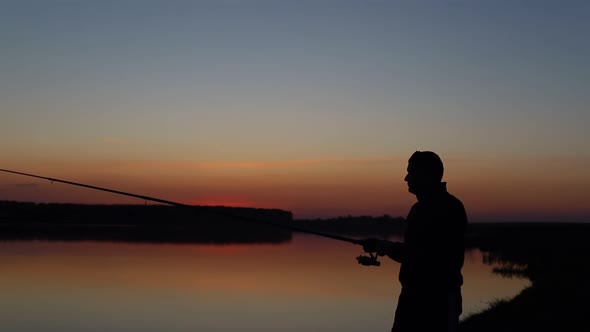 A Man Fishing  Throws the Fishing Rod  Sunset Silhouette