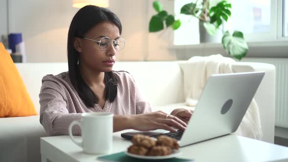 African Woman with Laptop at Table Works Online at Home Spbd