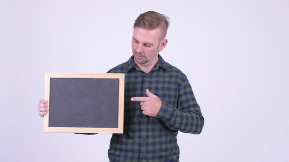 Portrait of Happy Blonde Hipster Man Holding Blackboard and Giving Thumbs Up