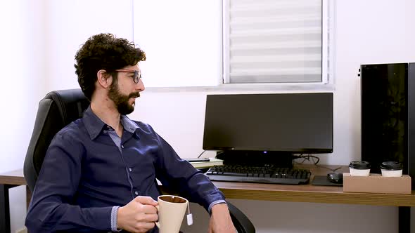 Handsome latin man drinking tea making a pause of work at office. Steady capture. Home office subjec