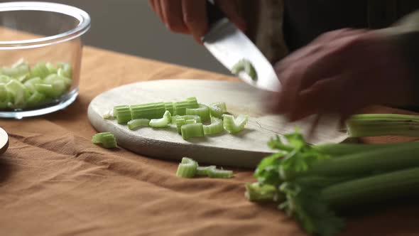 vegetarian man cuts Celery on a chalkboard in the kitchen with a knife