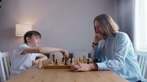 Father and Son on Selfisolation They Play Chess Sitting in the Living Room Entertainment During