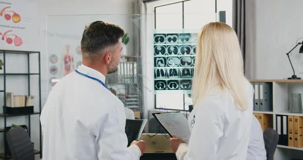 Male and Female Doctors which Learning Patient's X-ray and Discussing Treatment