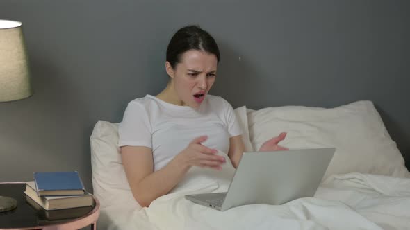 Young Woman with Laptop Having Loss in Bed 
