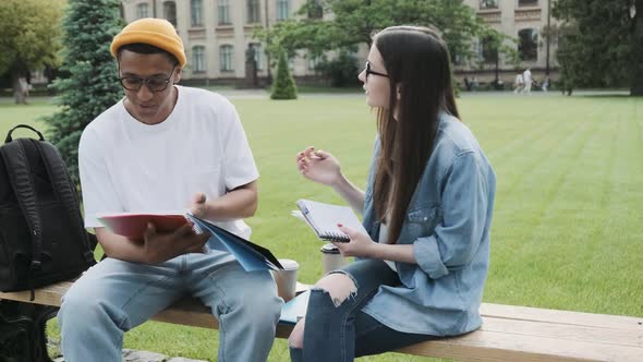 African American Male and Caucasian Female Students Working on the Project Outdoor in the Campus