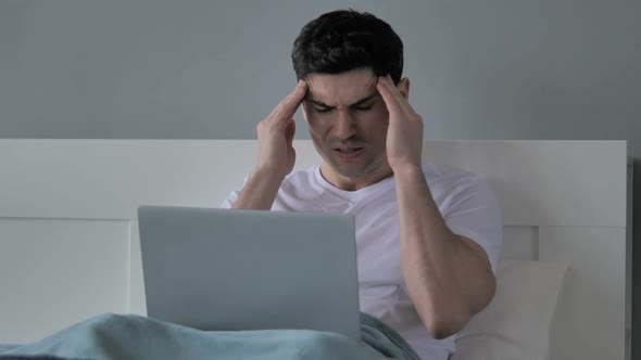 Headache Tense Young Man Working on Laptop in Bed