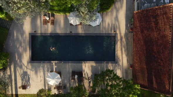 Aerial drone flying above of a beautiful swimming pool under sunshine reveal landscape of resort on