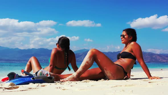 Beautiful beauty models relaxing in the sun at the beach on clean white sand and blue background 4K