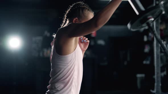 A Muscular Sportswoman is Doing Exercises in the Dark Gym