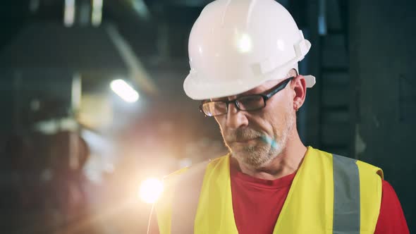 Male Engineer in Safety Wear with Light Flashing Behind Him