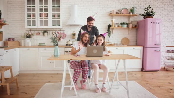 Happy Family with a Daughter Celebrating Birthday in Kitchen Using Laptop for a Video Call During