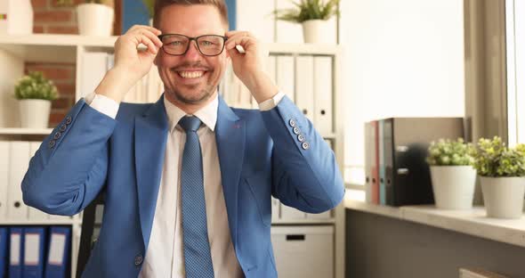 Young Smiling Businessman in Suit Sitting at Table and Putting on Glasses for Vision  Movie