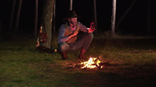 Cowboy Lights a Kerosene Lamp in the Forest at Night