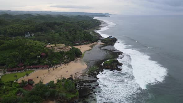 Aerial view of tropical beach in Gunung kidul, Indonesia with green and rocky cliff.