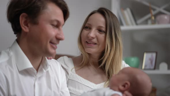 Rack Focus From Happy Caucasian Mother Putting Head on Husband Shoulder to Smiling Father Admiring