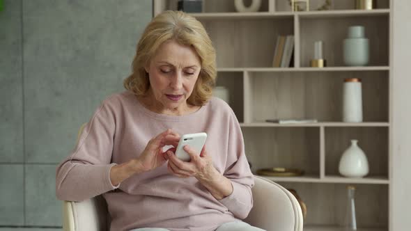 A Delighted Elderly Retired Grandmother Celebrates the Victory in the Game on Her Mobile Phone