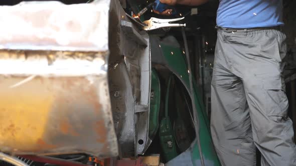 Male Hand of Repairman or Mechanic Worker Welds Metal Parts of Old Car with Welding Machine in