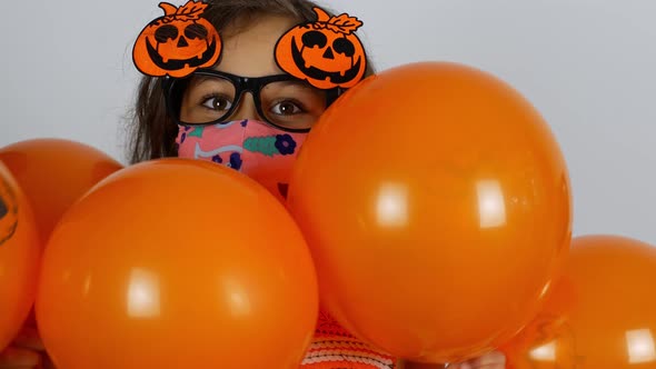 Halloween A little girl in a mask and a festive outfit is getting ready for Halloween. alt