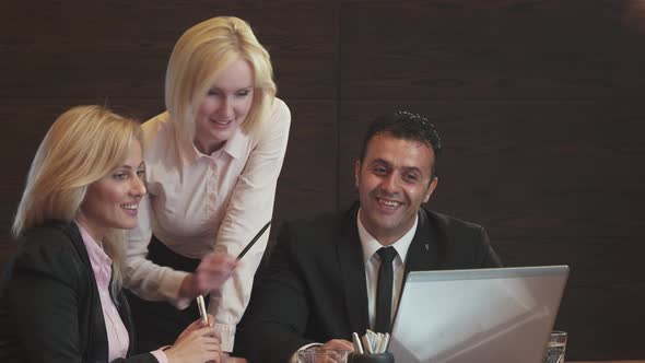 Three Business People Are Actively Discussing What They See in Their Laptop