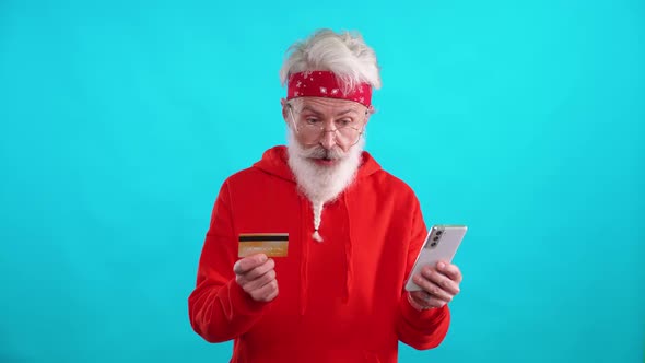 Grayhaired Man in a Red Hoodie Makes Successful Purchases Online Using a Smartphone and a Credit