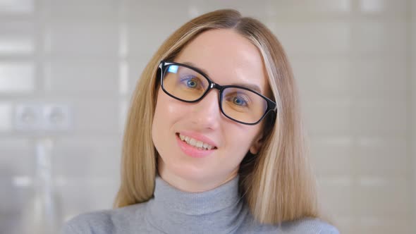 Cheerful white female in glasses talking on camera with smile and friendly expression in 4k video