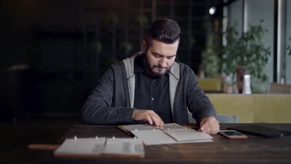 Handsome Man Is Reading Menu Sitting in a Restaurant in Dinner Break and Calling a Waiter