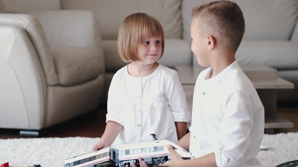 Two Children Playing with Toy Railroad Together at Home