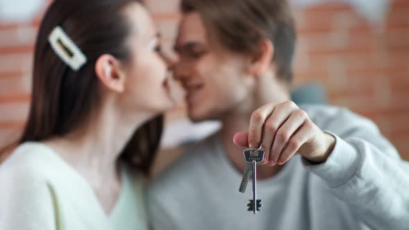 Closeup Male Hand Holding Keys From New Apartment Family Couple Feeling Love in Background