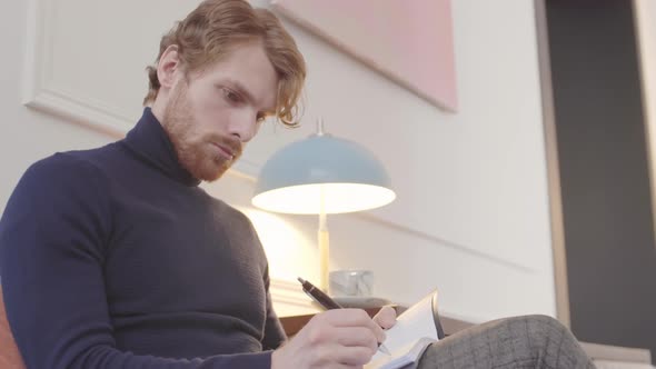 Man Writing in Notebook at Home