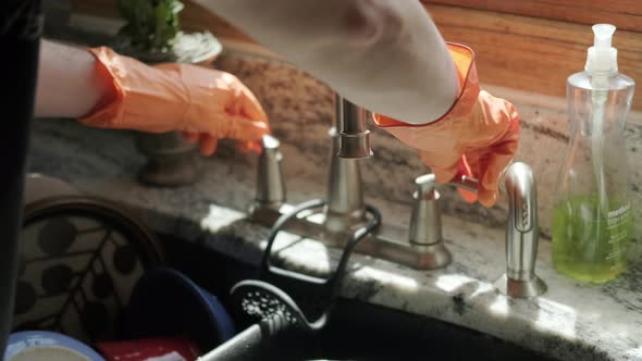 Hands in Orange Gloves Wash Dishes in the Kitchen