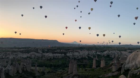 Hot-air balloons flying over the mountain landsape of Cappadocia, Turkey.	