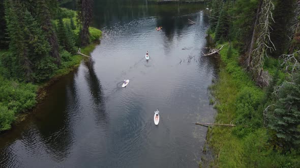 Drone shot of paddleboarders and kayakers from behind as they make their way down the Payette River