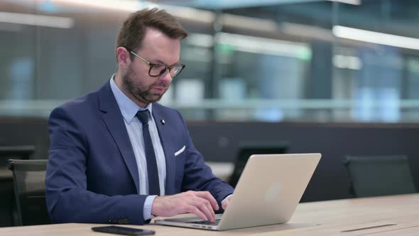 Middle Aged Businessman with Laptop Saying No By Finger Sign