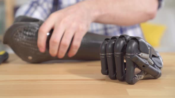 Young Man Removes a Cyber Prosthetic Hand Close Up