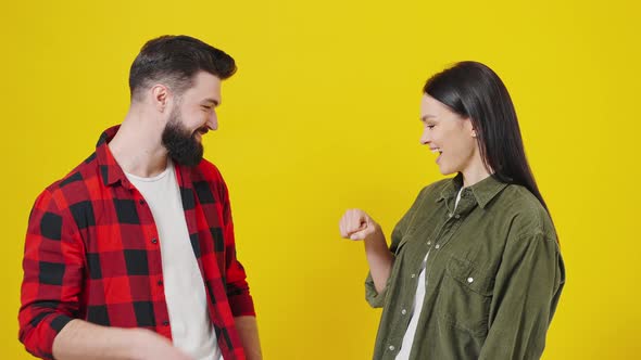 Portrait of Happy Young Couple on Yellow Background Hitting Fist on Fist Gesture Done Successful