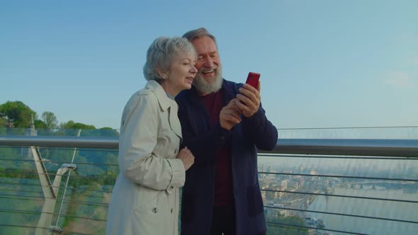 Lovely Senior Couple Reviewing Selfie Photo on Smartphone in City Park