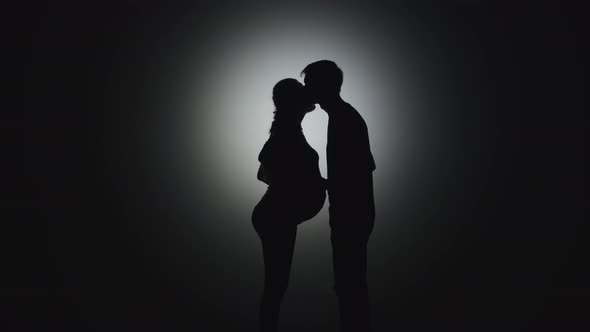 A Man Kisses a Pregnant Woman Without Faces