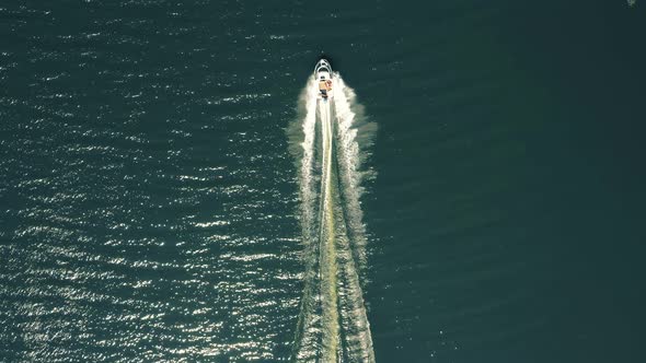 Luxury boat in dark color, fast movement on blue water, aerial view. Expensive luxury Italian boat m