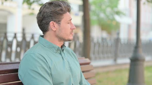 Portrait of Man Waiting while Sitting on Bench