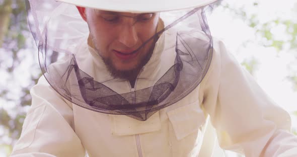 Portrait Young Male Bearded Beekeeper in White Protective Suit Picks Up From the Hive a Beehive