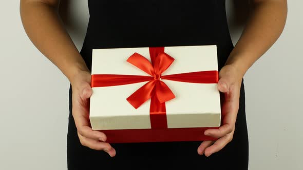 A woman in a black dress holds a gift in her hands. 4K video close-up of a Christmas present