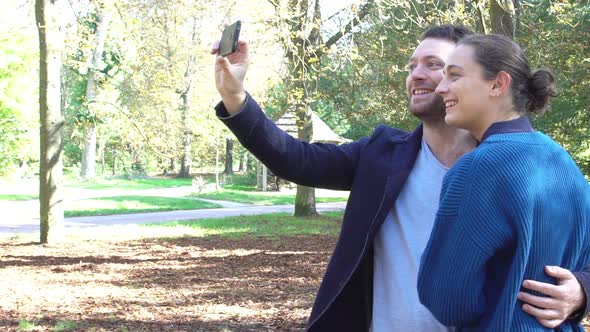 Slow motion shot of couple posing for selfie in park