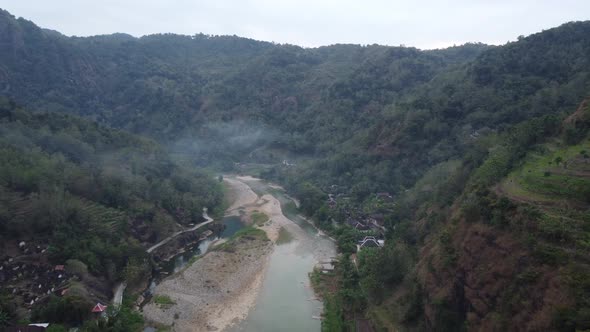 Beautiful aerial view of a river in the middle of the mountains in the morning with fog