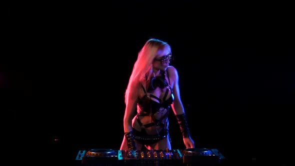 Erotic DJ Blonde Girl in Neon Light Behind the Decks