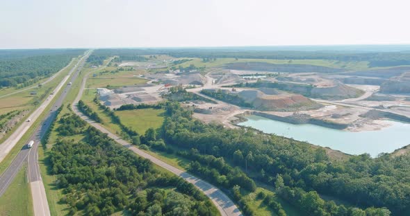 Open pit stone extraction in the canyon with deep green lake on aerial view