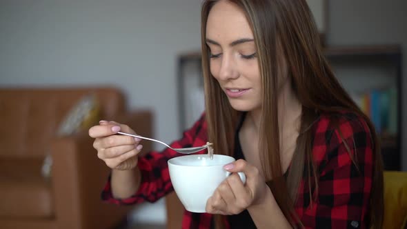 Beautiful young woman eats bowl of healthy granola