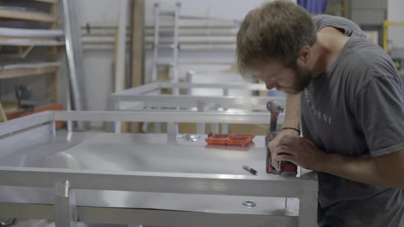 Worker drilling holes into a metal sheet