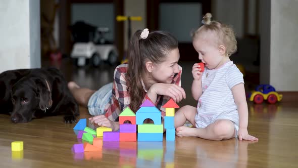 Mom plays in colorful figures with a small daughter on the floor